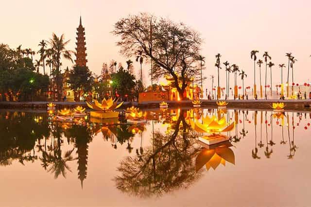 Chùa Trấn Quốc lung linh lúc hoàng hôn với ánh đèn từ hoa đăng hình bông sen phản chiếu xuống mặt nước hồ Tây tĩnh lặng