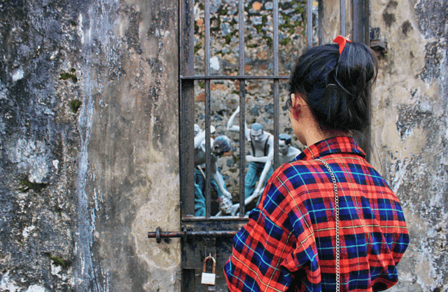 A young woman reflects with profound emotion while visiting the Côn Đảo prison historical site, deeply appreciating the sacrifices made by revolutionary soldiers for the peace we enjoy today.