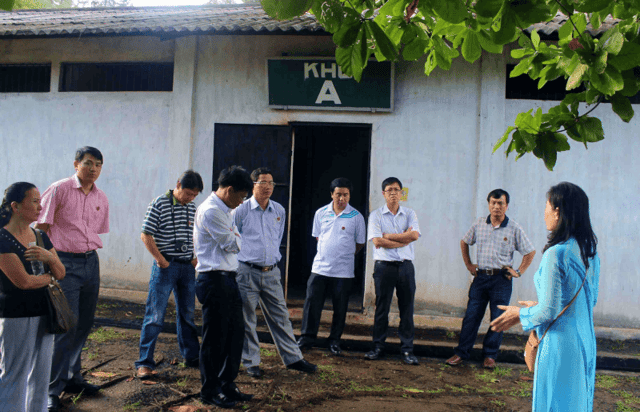 Visitors exploring the Côn Đảo prison historical site and listening to a tour guide narrate its history.