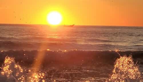 水面から太陽が顔を出す瞬間。まるで『海の瞳』、あるいは海の色を帯びた光の筋を放つ真っ赤な炎のよう
