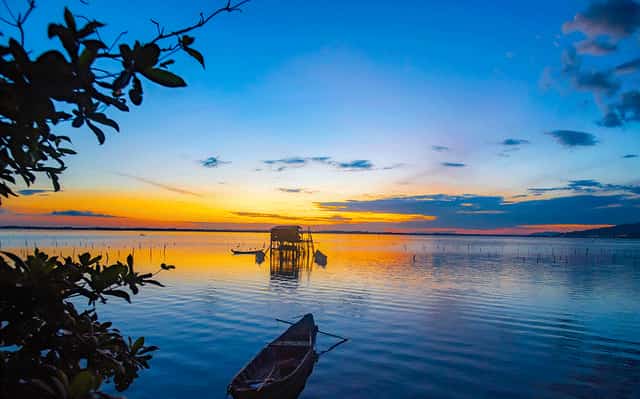 Xa xa một con thuyền lặng lẻ trong cảnh hoàng hôn trên đầm