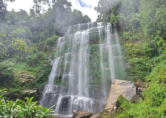 The waterfall cascades down the cliff face like a soft white silk ribbon